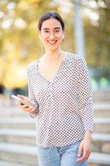 Fototapeta premium Attractive woman standing outside and listening to music from phone