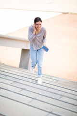 Young woman walking up the steps outside listening to music on phone