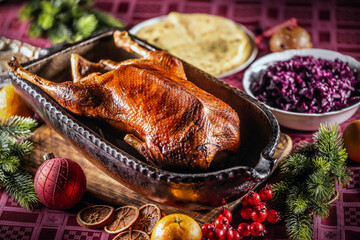 Christmas roast goose with red cabbage, potato dumplings in an original baking dish on the festive...