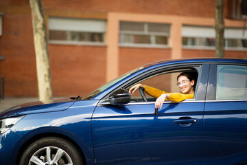 Smiling young woman driving new car in the city