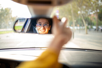Woman driver adjusting rear view mirror driving car