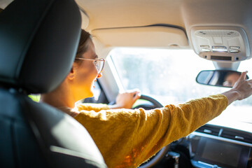 Woman driver adjusting rear view mirror of car