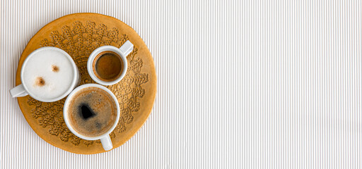 Three cups of coffee on a white texture background, flat lay.