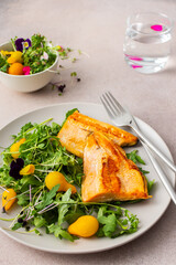 Delicious lunch with salad and fried char, healthy red fish and microgreens with cherry tomatoes, top view, copy space