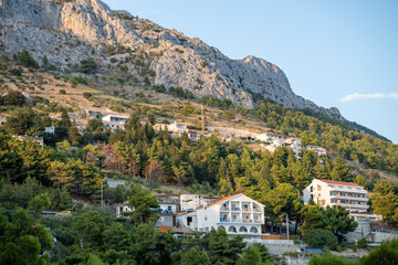Rows of houses built on the steep slopes of Dinara mountain and its rocky cliffs towering over the village