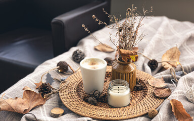 Cozy home composition with a cup of coffee, a candle and decorative details.