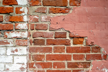 Fragment of old brickwork, close-up plan. A wall of red brick. Potholes and defects in a brick wall, side view. Flat lay, close-up. Cracks and defects in the red brick on the wall are illuminated.