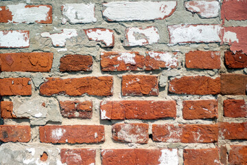 Fragment of old brickwork, close-up plan. A wall of red brick. Potholes and defects in a brick wall, side view. Flat lay, close-up. Cracks and defects in the red brick on the wall are illuminated.