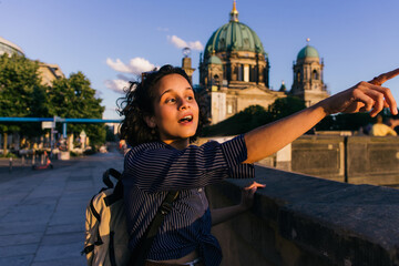 BERLIN, GERMANY - JULY 14, 2020: amazed young woman pointing away near blurred berlin cathedral.