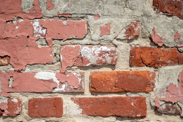 Fragment of old brickwork, close-up plan. A wall of red brick. Potholes and defects in a brick wall, side view. Flat lay, close-up. Cracks and defects in the red brick on the wall are illuminated.