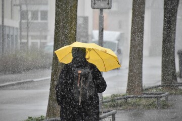 A person wearing black and holding an umbrella and walking in rainy weather a rainy