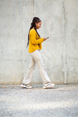 Stylish young african woman texting on mobile phone outdoors in city