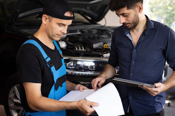 Car Service Employees Inspect the Bottom and Skid Plates of the Car. Manager Checks Data on a...