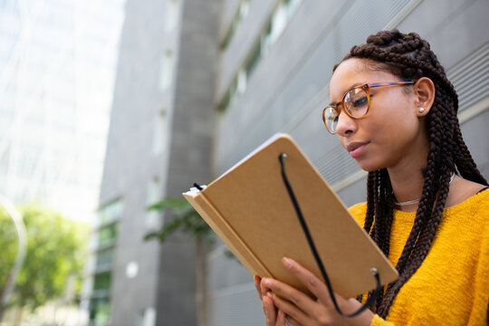 African american female university student reading book at campus