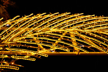 Street decor - feather. Close-up of yellow neon lighting and garland lights from LED bulbs....