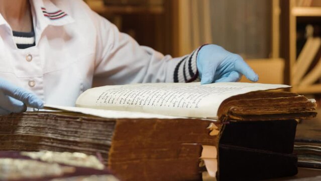 The master is restoring an old book. Stock footage. Close up of a book restorer hands turning pages slowly.