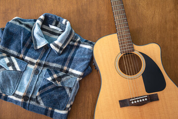 Acoustic guitar and shirt on a wooden background.