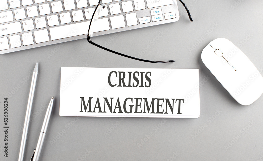 Aufkleber crisis management text on paper with keyboard on grey background