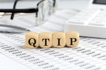 wooden cubes with the word QTIP Qualified Terminable Interest Property on a financial background with chart, calculator, pen and glasses, business concept.