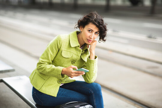 Portrait Of Beautiful Woman Using Mobile Phone At City Bus Stop