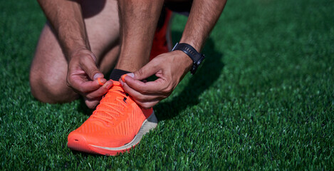 Sport man athlete tying laces for jogging on treadmillat the stadium.