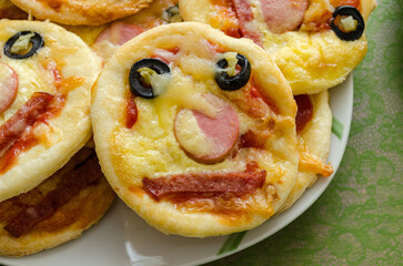 children's mini pizza. Small pizza with sausage, sausages and olives folded in the form of a smiley. High quality photo