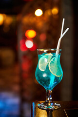 Blue Alcoholic cocktail with lemon slices on the bar counter of a nightclub