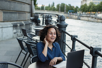 happy young freelancer using laptop while sitting on summer terrace near river in berlin.