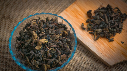 Dried roasted green tea leaves on the bowl on burlap background, Japanese tea, Houji tea