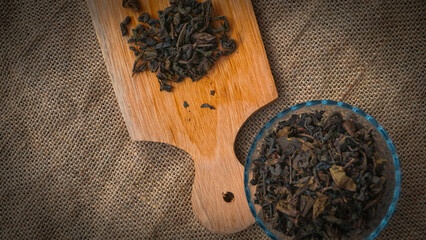 Dried roasted green tea leaves on the bowl on burlap background, Japanese tea, Houji tea