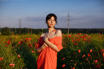 a beautiful girl in a beautiful red dress with a bouquet of red poppies, in a field, on a summer day