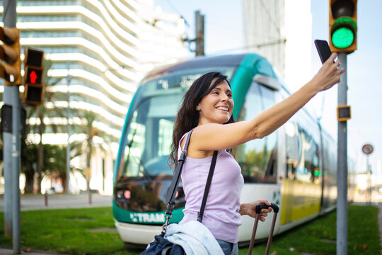 Happy woman taking selfie in front of city tram