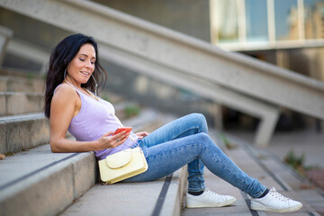 Relaxed woman listening music on mobile phone outdoors in city