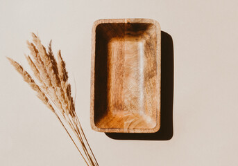 Empty wooden tray with sunlight and beautiful bouquet of dry plants and shadows