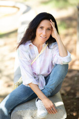 Beautiful woman sitting outdoors on park bench