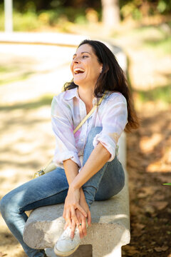Mature woman laughing outdoors on park bench
