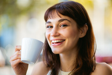 Attractive young woman with cup of coffee at outdoor cafe