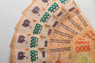 Billetes de 1000 pesos argentinos desplegados en abanico sobre fondo blanco
