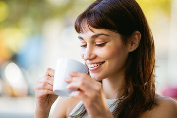 Beautiful young woman drinking coffee at cafe and smiling