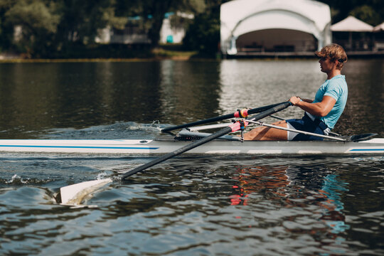 Sportsman single scull man rower rowing on boat.