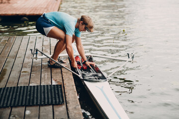 Sportsman single scull man rower prepare to competition with boat.
