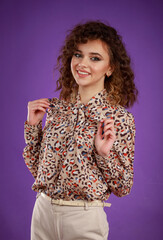 A vertical portrait of a young curly-haired girl smiling and put her hands to her chest