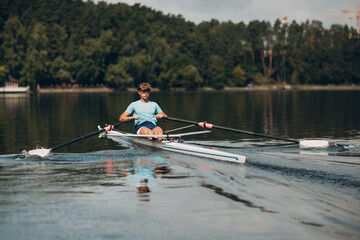 Sportsman single scull man rower rowing on boat. - obrazy, fototapety, plakaty