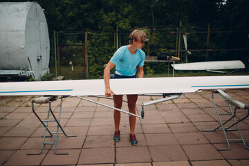 Sportsman single scull man rower prepare to competition with boat. © primipil