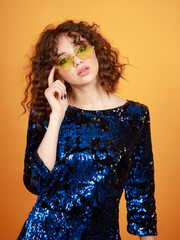 Vertical photo of young curly-haired girl stands on orange background