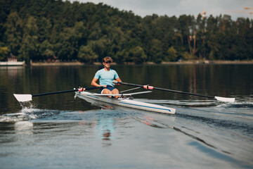 Sportsman single scull man rower rowing on boat.