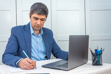 Fototapeta premium Man in suit sitting near laptop working remotely