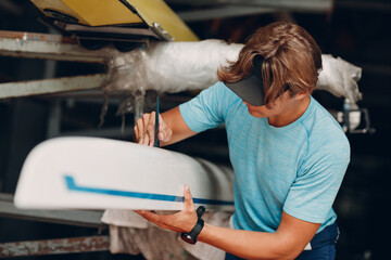 Sportsman single scull man rower sportsman checking carbon surface of boat. © primipil