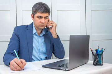 Man in suit sitting near laptop working remotely