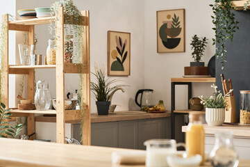 Horizontal image of modern domestic kitchen with paintings on the wall and wooden shelves